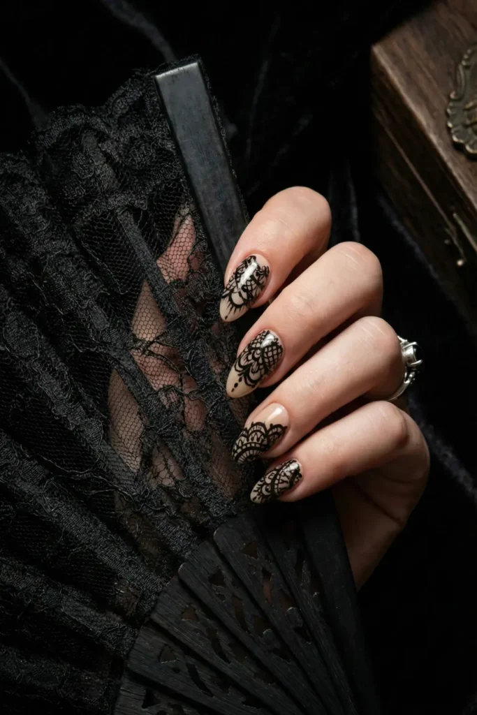 Black lace nail art on almond shaped nails for a gothic chic look.