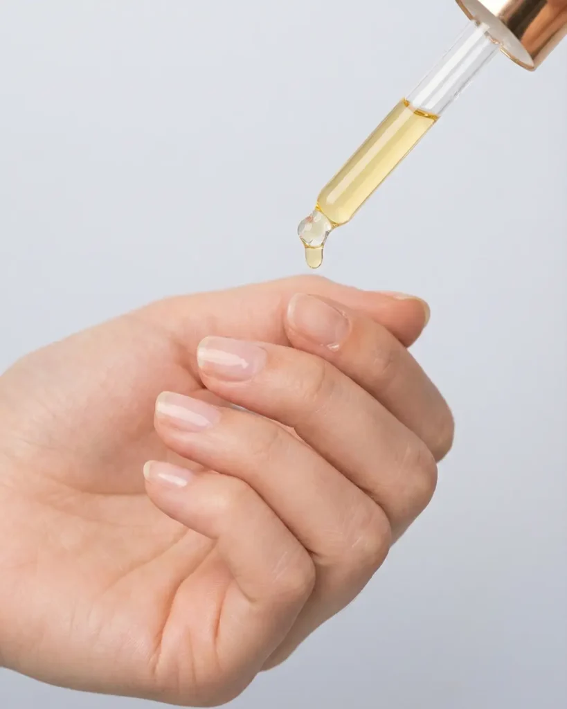 Applying cuticle oil to fresh manicured nails to maintain hydration and health.