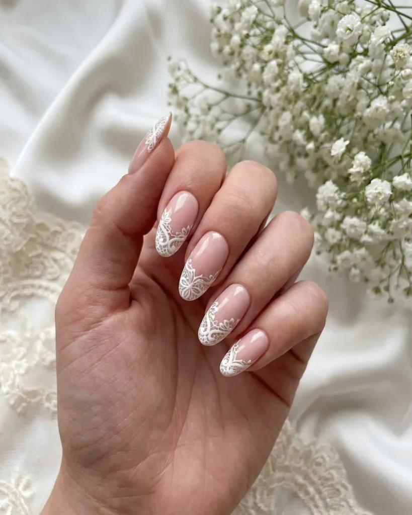 Laced Up nail trend 2026 showing a soft nude manicure with intricate hand-painted white lace French tips.